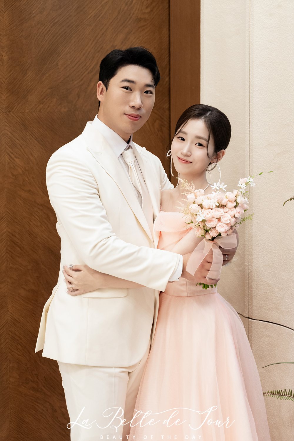 라벨드쥬 합정 웨딩시그니처 아너스홀 본식스냅 — 무늬목 벽 앞 두 사람